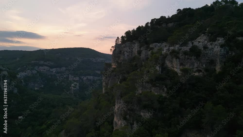Flying by sheer limestone cliffs over quiet valley at sunset Flying by sheer limestone cliffs over quiet valley at sunset