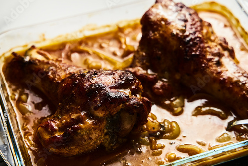 Smothered or stewed Turkey wings in a rectangular baking dish. Roasted to a crisp, the wings lie drowned in a thick gravy with vegetables. Food photo.