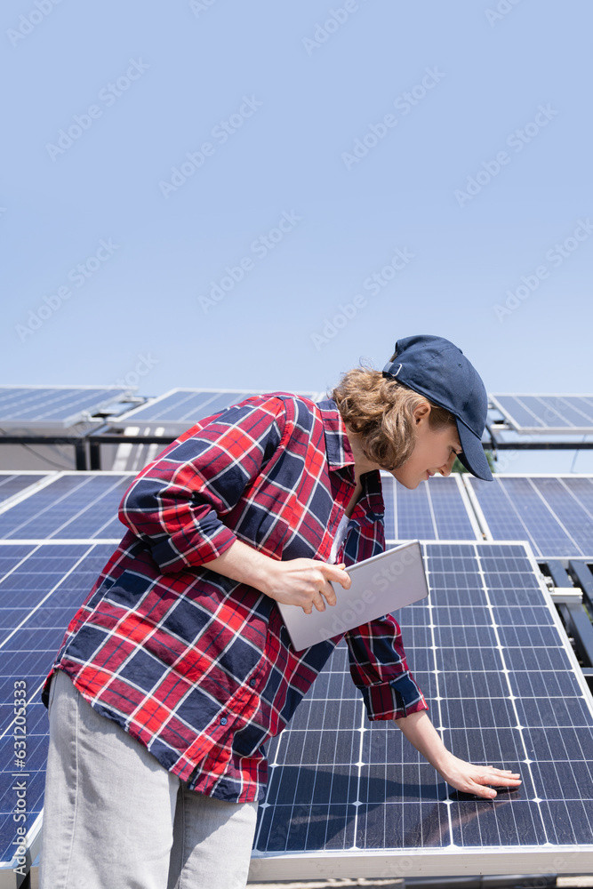 Woman with digital tablet touching solar panel