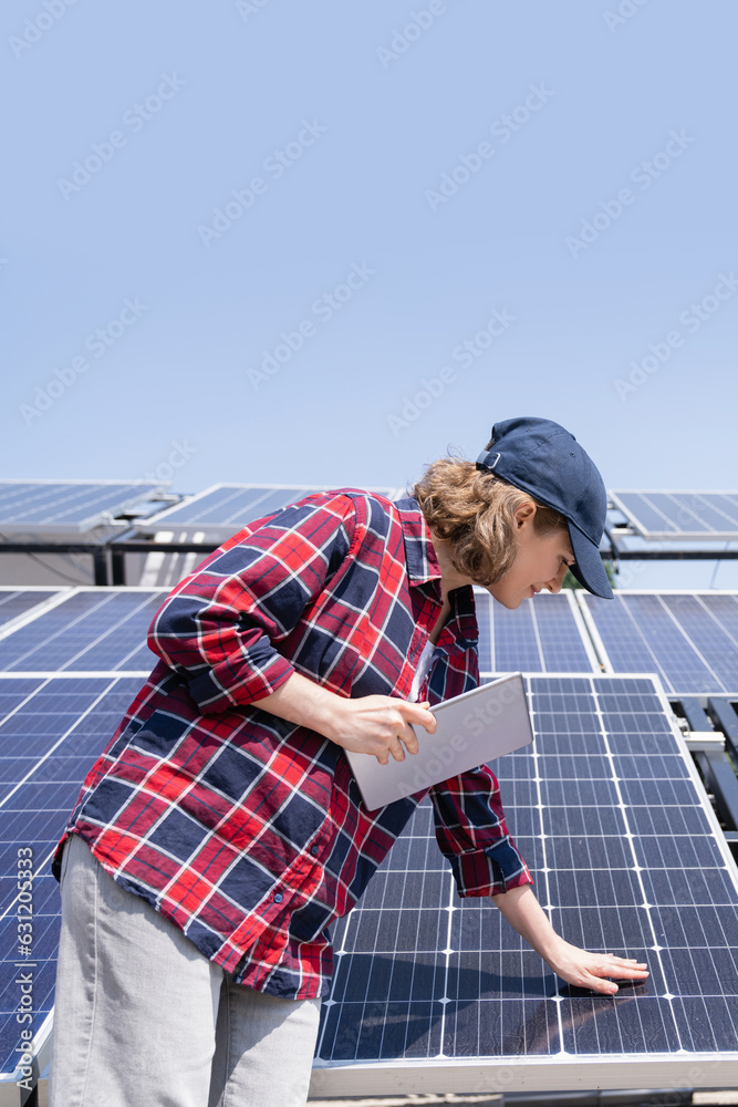 Woman with digital tablet touching solar panel Woman with digital tablet touching solar panel