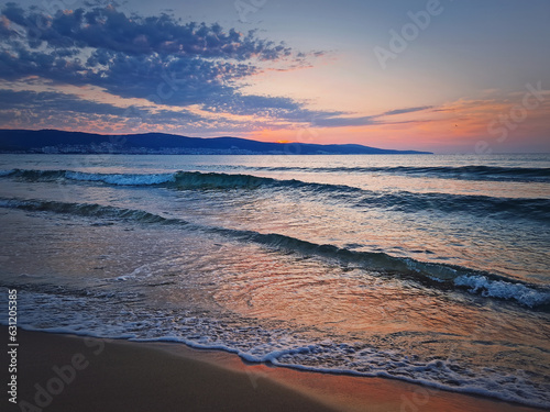 Sunrise at the sea with foamy waves on the sand and colorful sky at the horizon. Summer and travel background  Sunny Beach coastline in Bulgaria