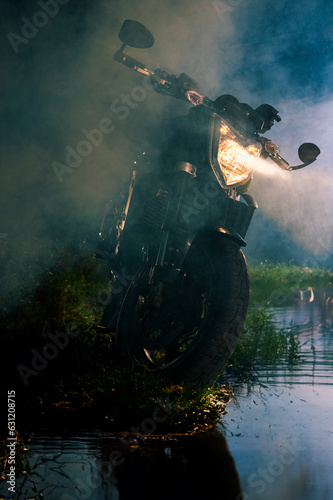 Motorrad im Abendlicht mit leuchtendem Scheinwerfer am See
