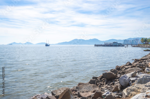 Beach with the silhouette of the city of floriano ́polis in santa catarina, landscape with sea, blue sky, stones and buildings photo