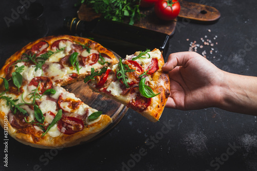 Pizza with ham,tomatoes and mozzarella on a dark background