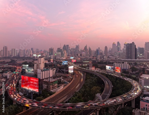 Panorama of Bangkok at dusk with skyscrapers in background & heavy traffic on elevated expressways & circular interchanges ~ Night scape of Bangkok with busy traffic on intertwined highway overpasses
