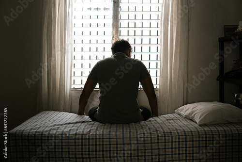 Desperate man in silhouette sitting on the bed alone. masculinity and emasculation concept.