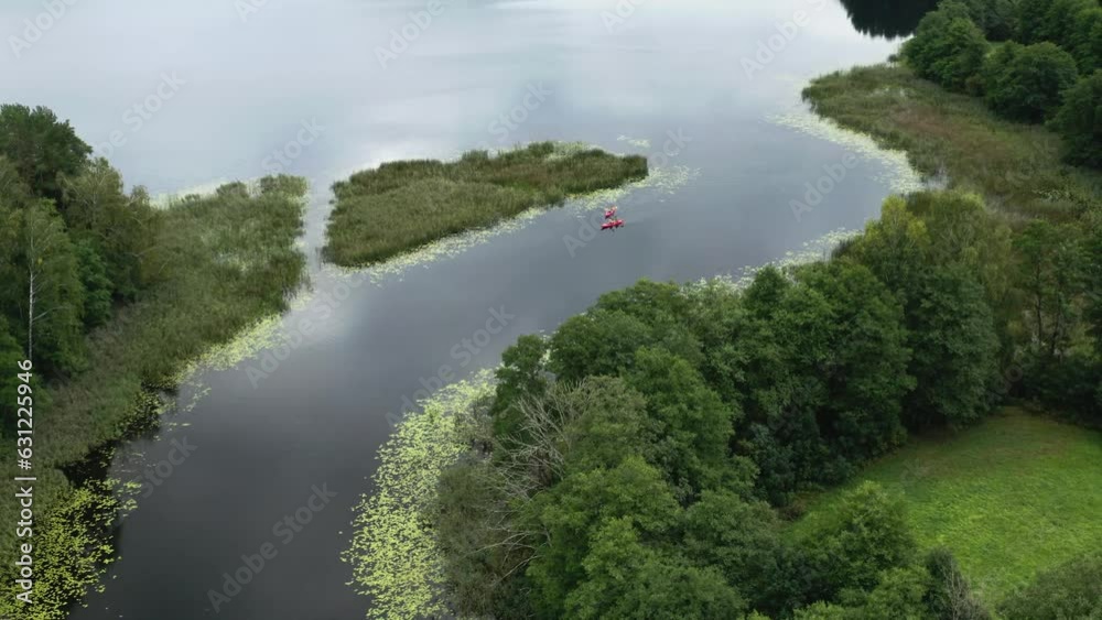 Drone view over red kayaks driving on a river between green fields Drone view over red kayaks driving on a river between green fields