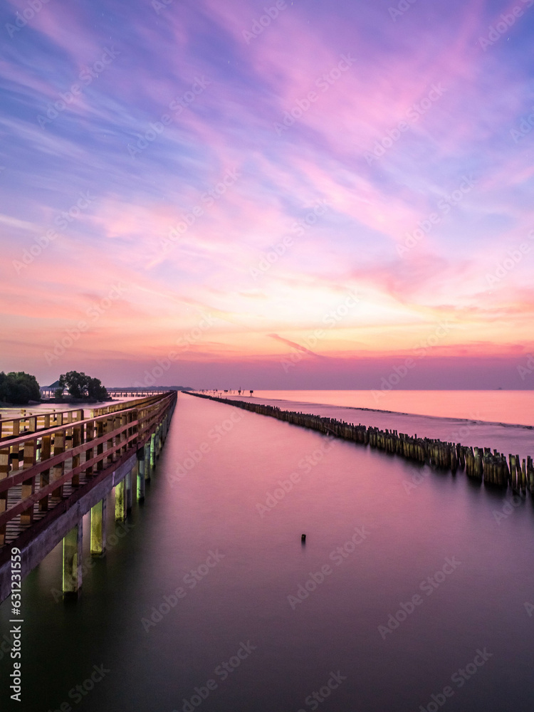 Obraz premium Sea view near mangrove forest with man made wooden barrier for wave protection, under morning twilight colorful sky in Bangkok, Thailand