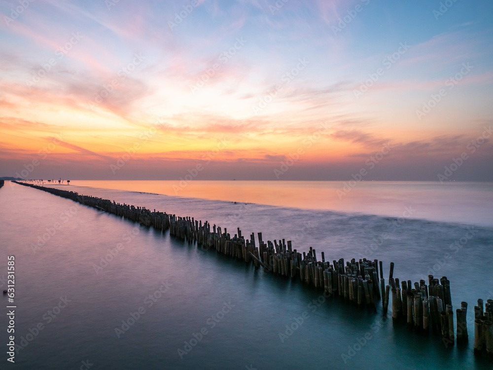 Obraz premium Sea view near mangrove forest with man made wooden barrier for wave protection, under morning twilight colorful sky in Bangkok, Thailand