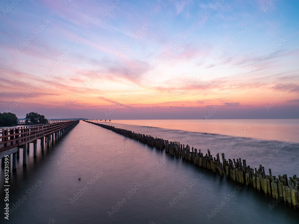 Obraz premium Sea view near mangrove forest with man made wooden barrier for wave protection, under morning twilight colorful sky in Bangkok, Thailand