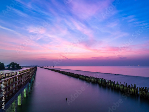 Sea view near mangrove forest with man made wooden barrier for wave protection, under morning twilight colorful sky in Bangkok, Thailand © jeafish