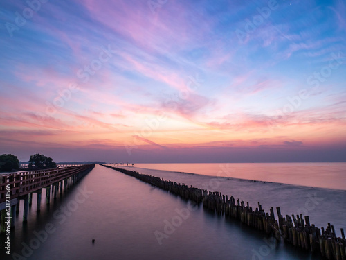 Sea view near mangrove forest with man made wooden barrier for wave protection, under morning twilight colorful sky in Bangkok, Thailand © jeafish