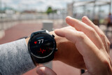 Close-up of smart watch health tracker with heart rate shown on the screen. Modern stylish and innovation wearable device. athlete checks his heart rate before training at the stadium. heart beat