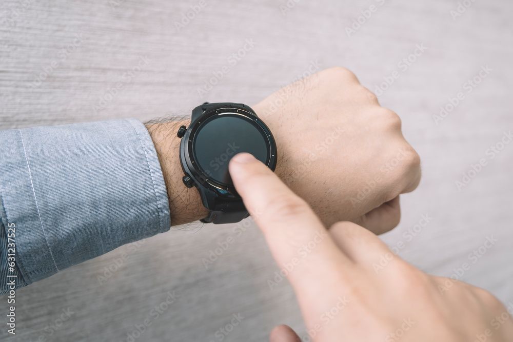 Fototapeta premium Fitness watch on mans forearm showing date, time, heart rate step counter.