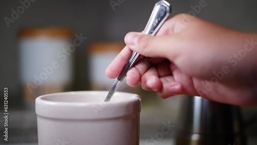 Person taking a spoon full of sugar or salt from a jar and dropping it in slow motion