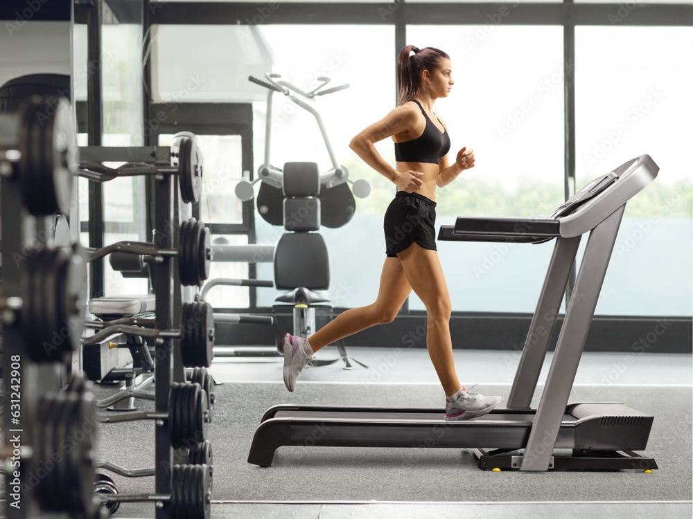 Fototapeta premium Fit young female running on a treadmill in a gym