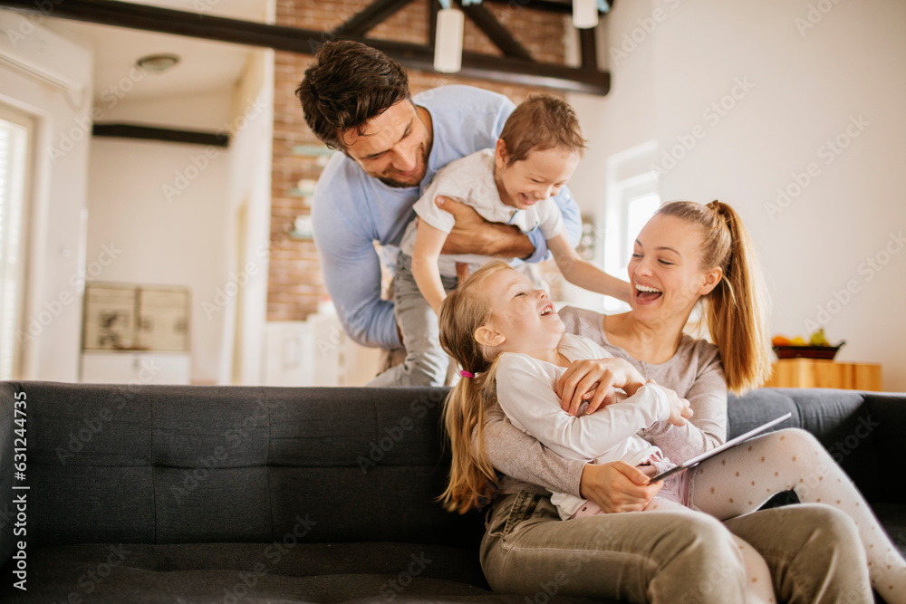 Young family playing on the couch together in the living room at home