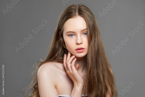 beautiful model looking at camera posing in studio. close-up girl with light healthy skin and blue eyes looks into the camera with flowing long hair 