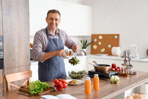 Mature man making vegetable salad in kitchen