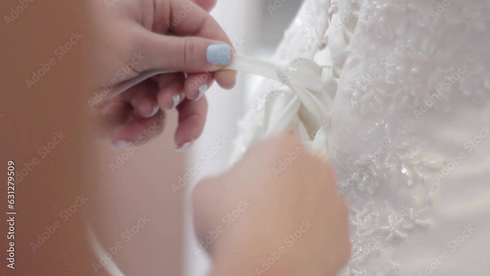 Bride being tightened corset on white wedding dress on wedding day