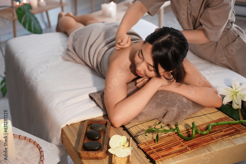 Pretty young Asian woman having massage in spa salon