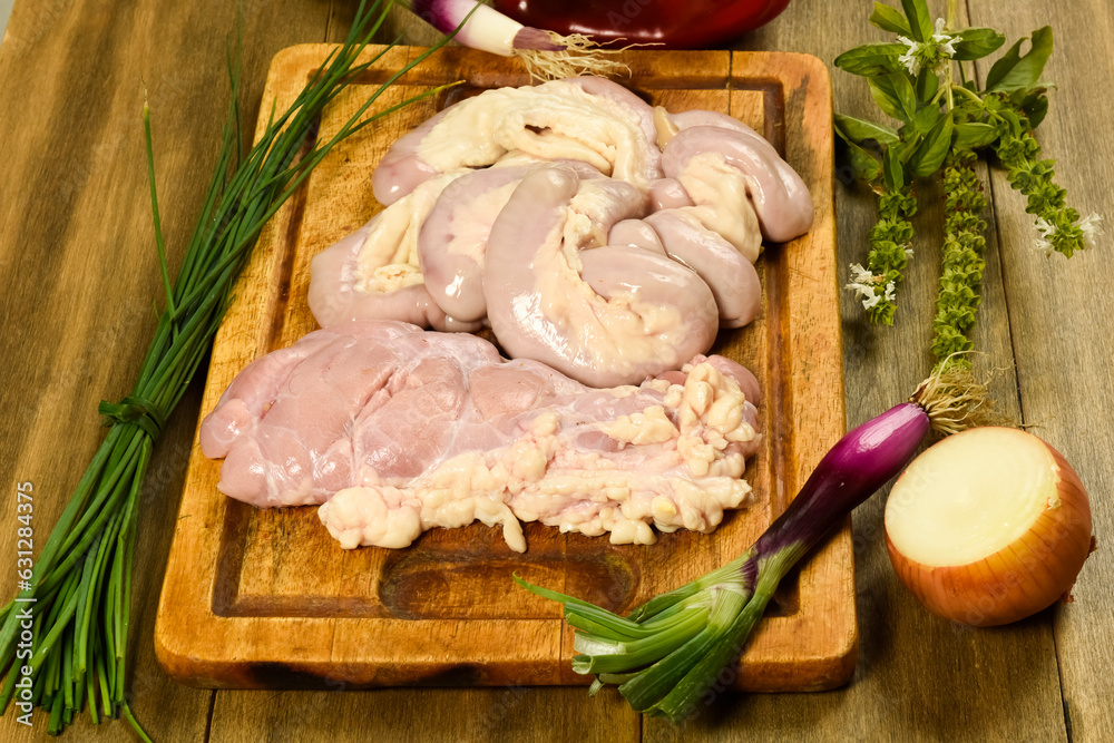Cow bowels presented on a wooden board with ingredients, ready to grill Cow bowels presented on a wooden board with ingredients, ready to grill