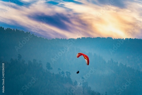 bright red para sailing being done in front of the majestic himalaya mountains in manali, bir, billing
