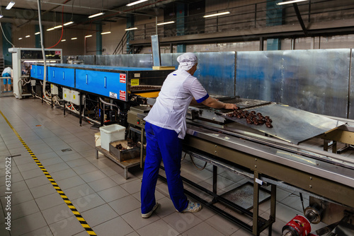 Confectionery worker sorting zephyrs on conveyor belt