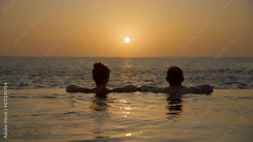 Couple entering private pool at sunset and kissing Couple entering private pool at sunset and kissing
