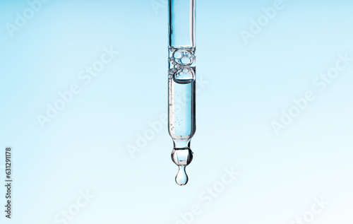 Pipette serum with clear liquid niacinamide, hyaluronic or Aha Bha acids on a blue white isolated background. Textured swatch skincare. Laboratory cosmetic