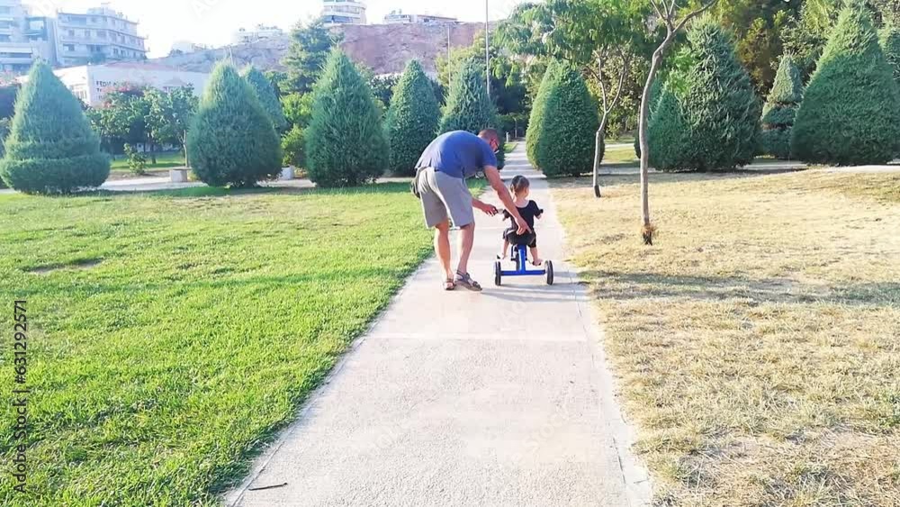 Happy young father teaching his daughter to ride bike in park. learning cycling Happy young father teaching his daughter to ride bike in park. learning cycling