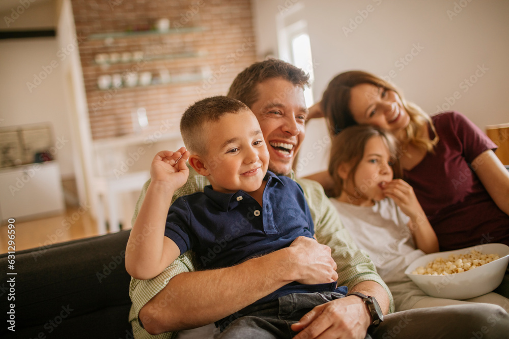 Young family watching the tv on the couch in the living room at home Young family watching the tv on the couch in the living room at home