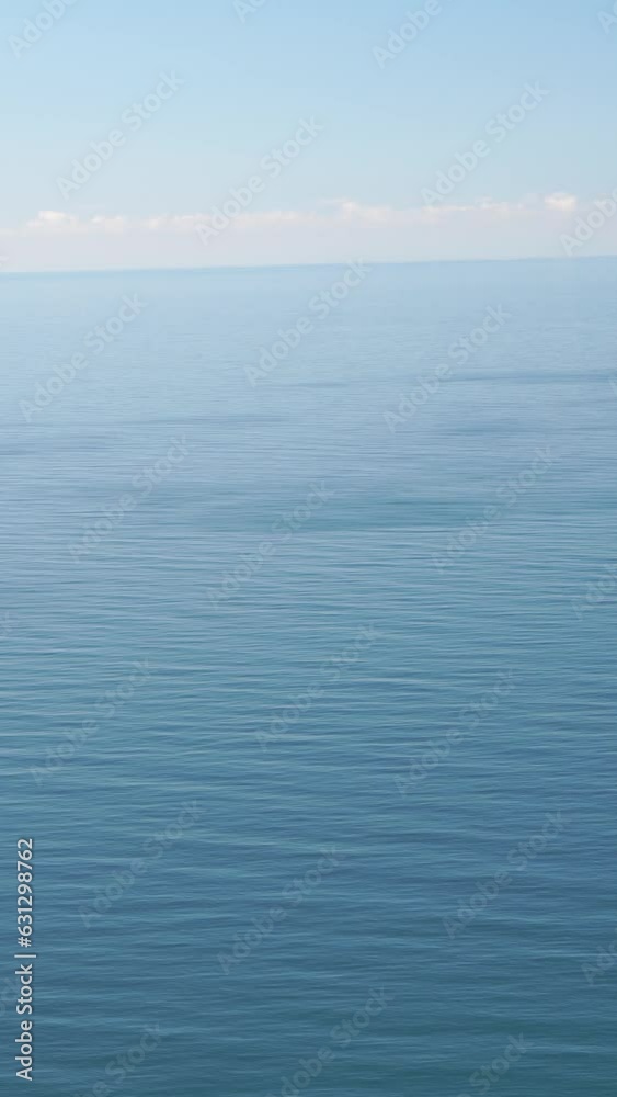 Vertical aerial view on sea water surface, camera flies over clear sea water. Sun glare. Abstract nautical summer ocean nature. Holiday, vacation and travel concept. Nobody. Vertical video Vertical aerial view on sea water surface, camera flies over clear sea water. Sun glare. Abstract nautical summer ocean nature. Holiday, vacation and travel concept. Nobody. Vertical video