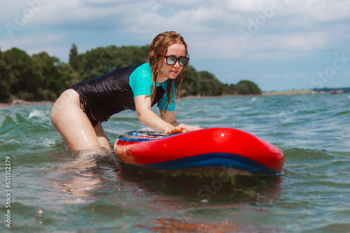 Young woman pushing a sup board in the sea. Healthy and fit life in the nature.