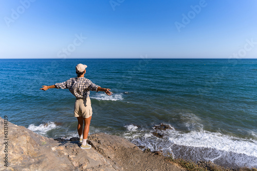 tourist girl with a backpack on her back in the summer stands on top of a mountain