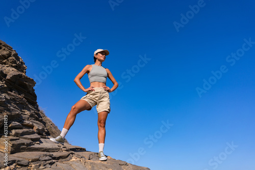 tourist girl with a backpack on her back in the summer stands on top of a mountain