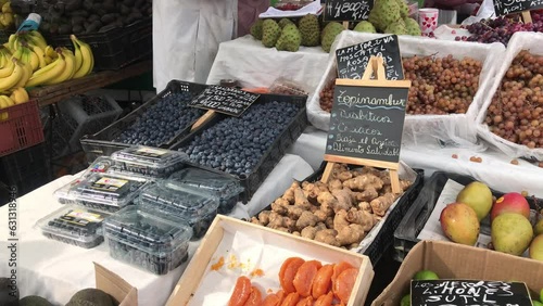 Latin American market exploration: seller, customer and colorful and fresh fruits and roots in crates on a sunny day