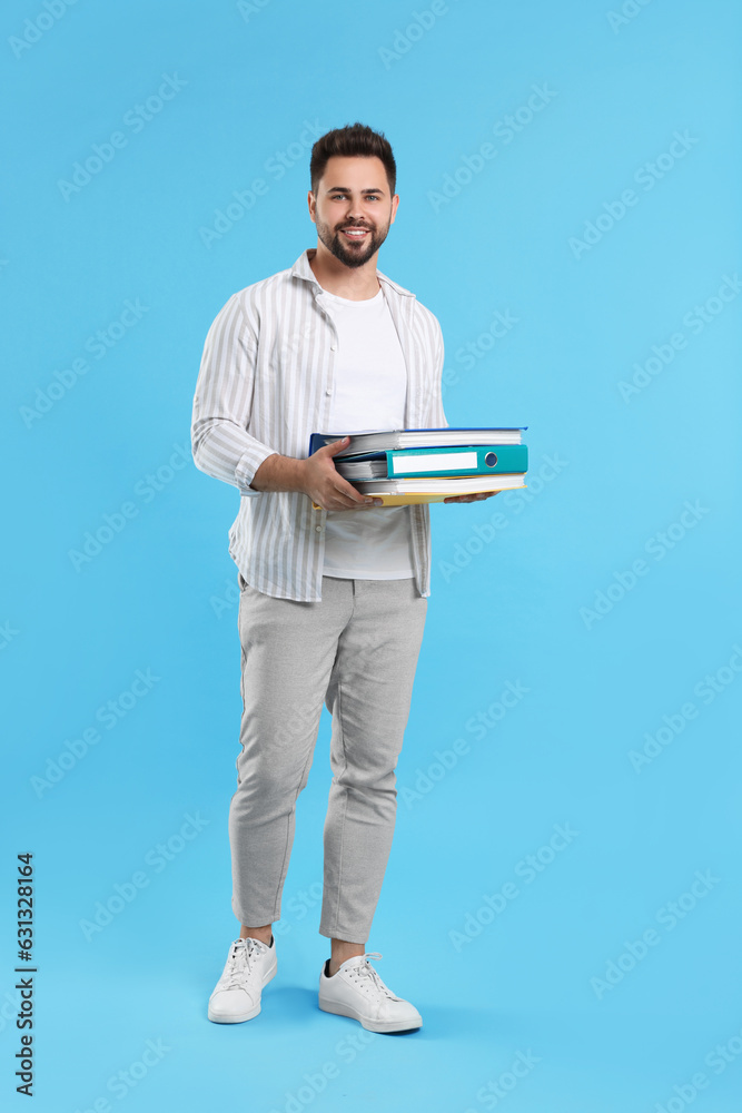 Happy man with folders on light blue background Happy man with folders on light blue background