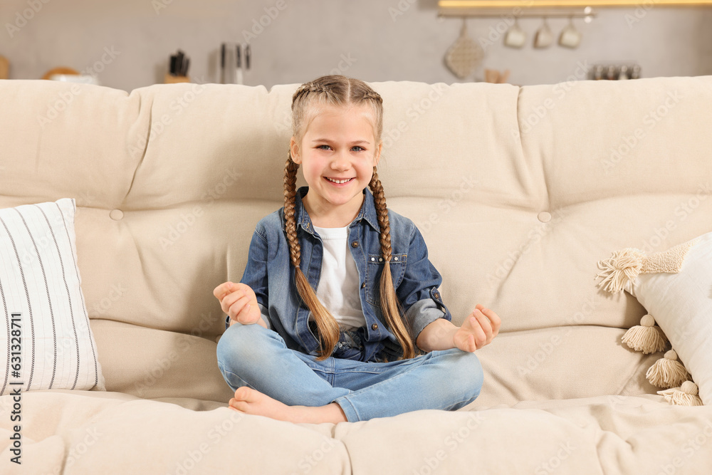 Little girl meditating on soft sofa at home Little girl meditating on soft sofa at home