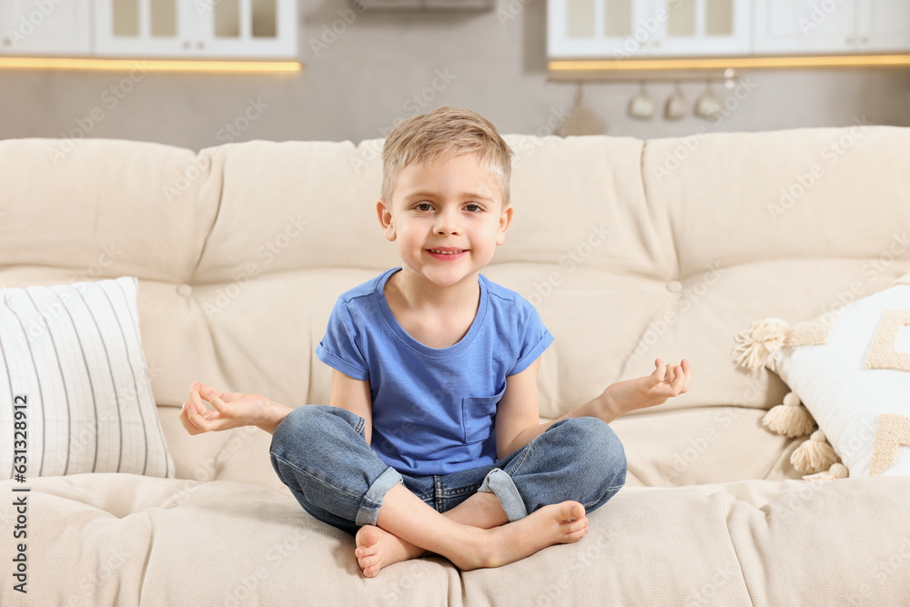 Little boy meditating on soft sofa at home Little boy meditating on soft sofa at home