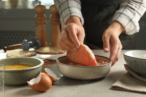 Obraz na płótnie Woman cooking schnitzel at grey table indoors, closeup