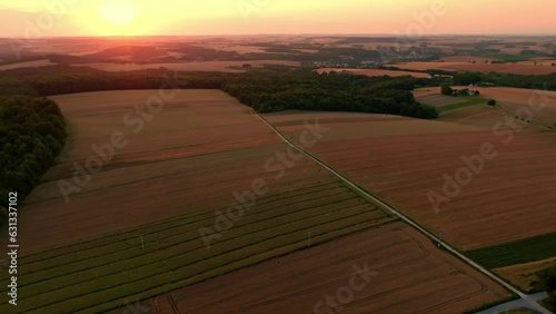 Sunset over a dirt road running between agricultural fields from a drone, aerial view. The concept of farming, agricultural landscapes.