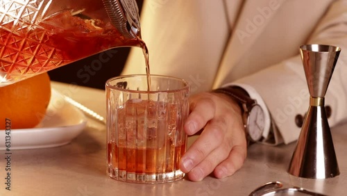 Bartender pouring a Negroni cocktail into a glass