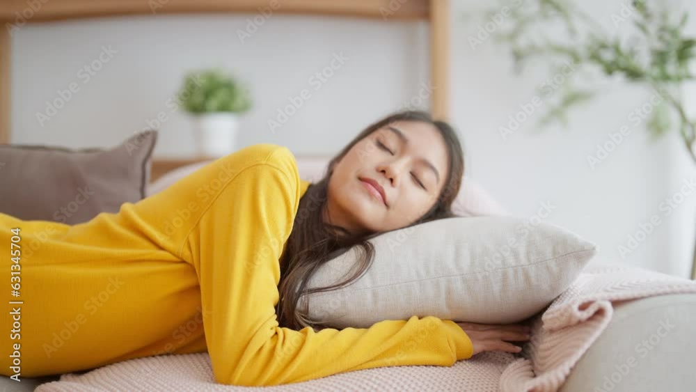 Asian woman resting at home on couch, feeling exhausted after work, lacking energy, or overworked, too tired, and lacking motivation Asian woman resting at home on couch, feeling exhausted after work, lacking energy, or overworked, too tired, and lacking motivation