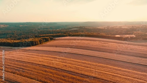 Sunset over a beautiful hilly farmland seen from a drone, aerial view. The concept of farming, agricultural landscapes.