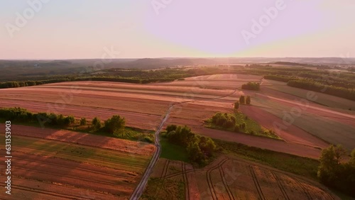 Sunset over a beautiful hilly farmland seen from a drone, aerial view. The concept of farming, agricultural landscapes.