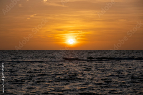 Ocean sunset. Big white sun on dramatic bright sky background, soft evening horizont over sea dark water