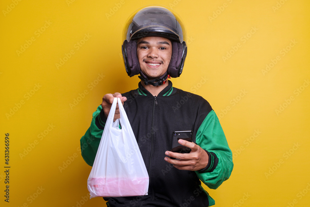 Asian online taxi driver wearing green jacket holding food wrapped in plastic while holding phone Asian online taxi driver wearing green jacket holding food wrapped in plastic while holding phone