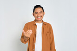 Happy young Asian man wearing casual shirt showing come on gesture with hands isolated on white background