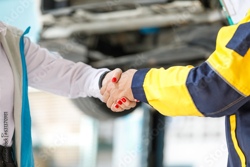 Close-up photo of a young artist shaking hands with female customers Complete vehicle inspection Satisfied customers in professional service garages